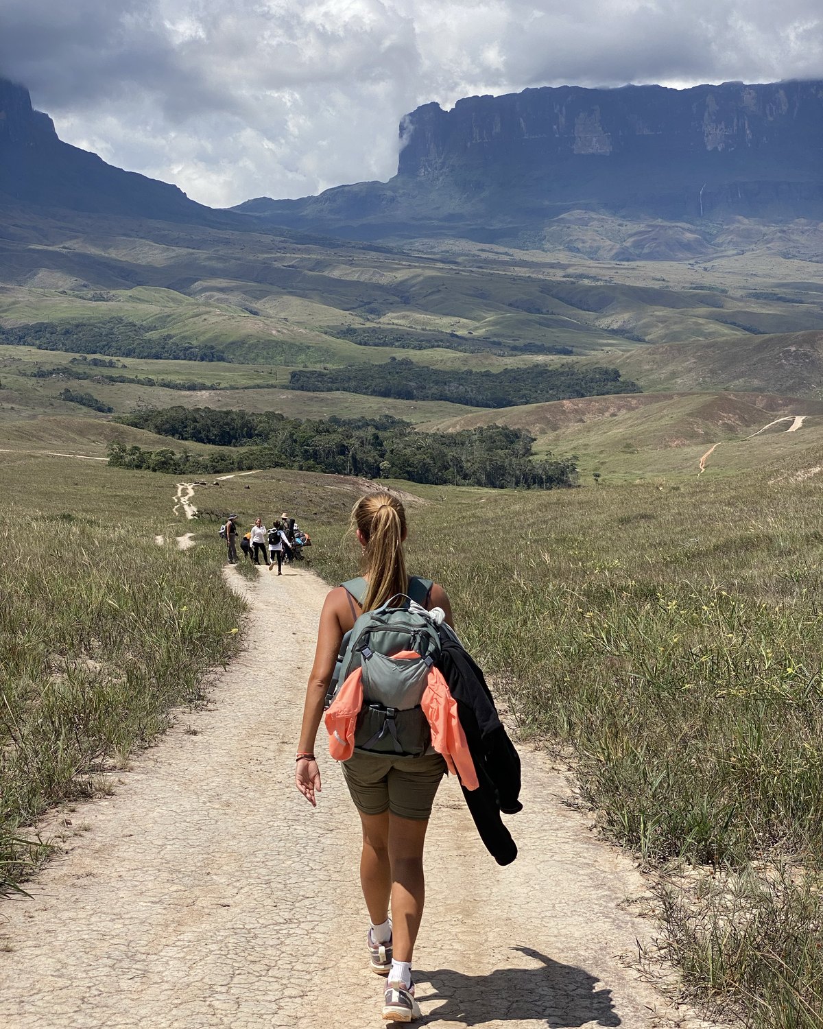 Dos personas caminando por la sabana abierta con la montaña de fondo