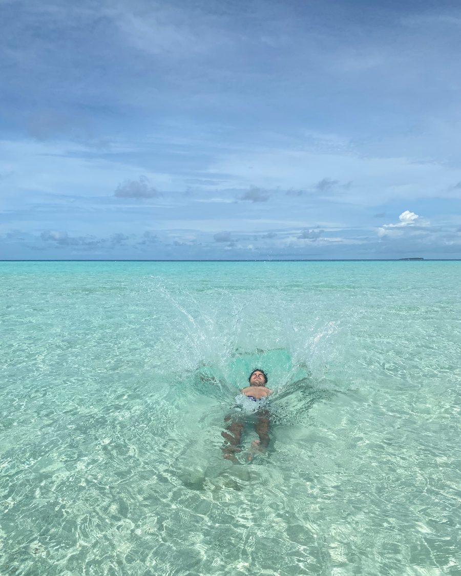 Un bañista salpicando en el agua transparente de La Tortuga