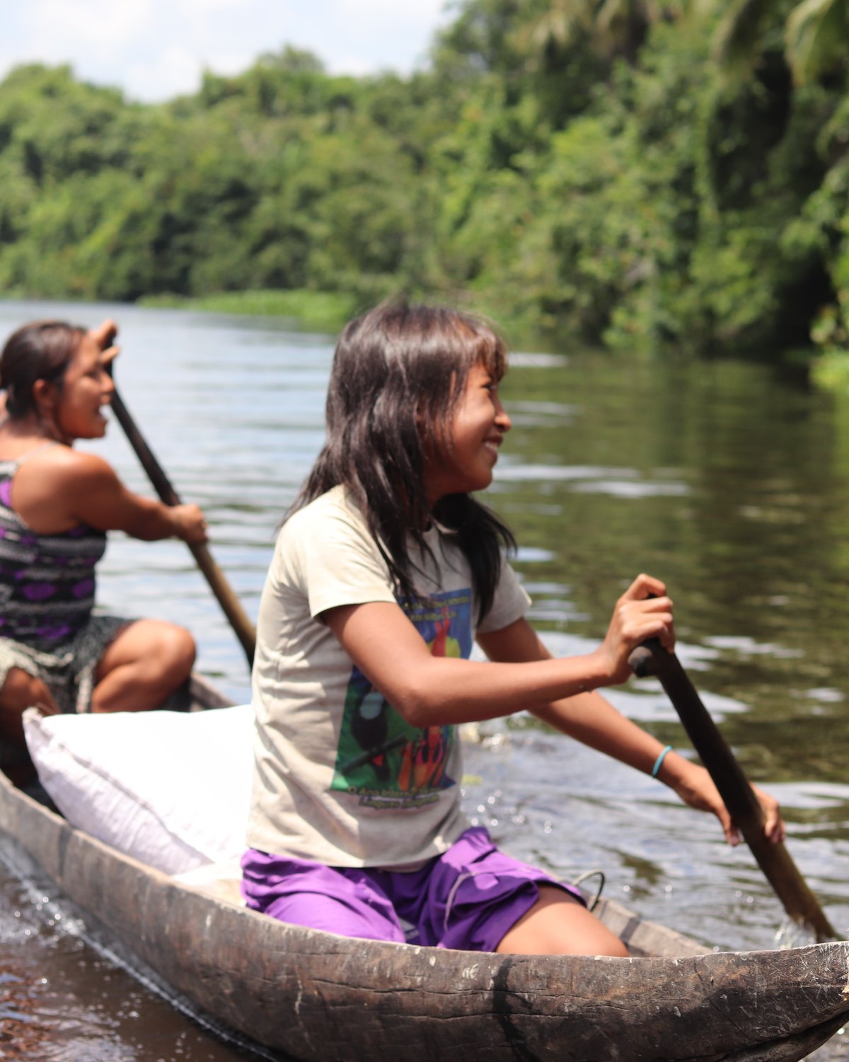 Dos niñas warao remando una curiara por un caño del Delta