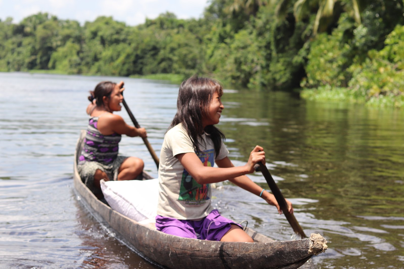Dos niñas warao remando una curiara por un caño del delta